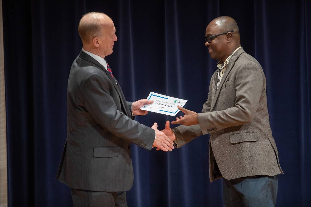 Dean Potteiger shaking hands with the first place winner, presenting him the award
